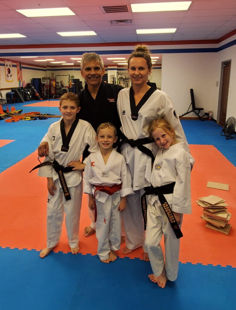 An adult black belt and her three young children with Master Gonzalez at Chang Lee's Taekwondo in Allen, TX