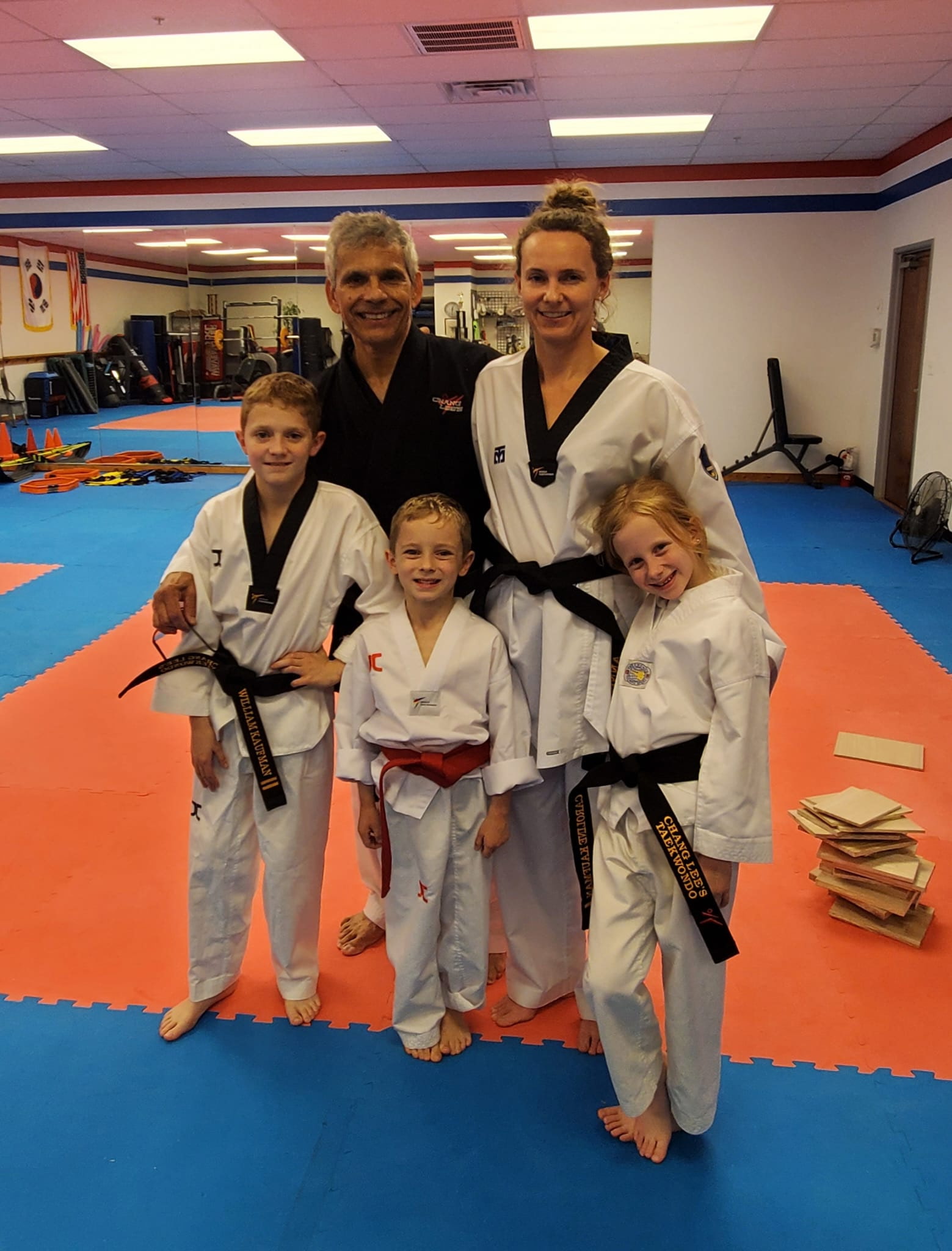 An adult black belt and her three young children with Master Gonzalez at Chang Lee's Taekwondo in Allen, TX