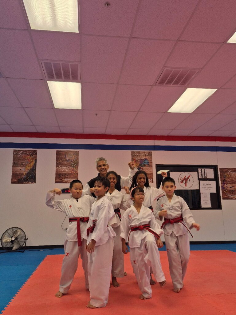 Kids and teens in red belts flexing after class at Chang Lee's Taekwondo in Allen, TX